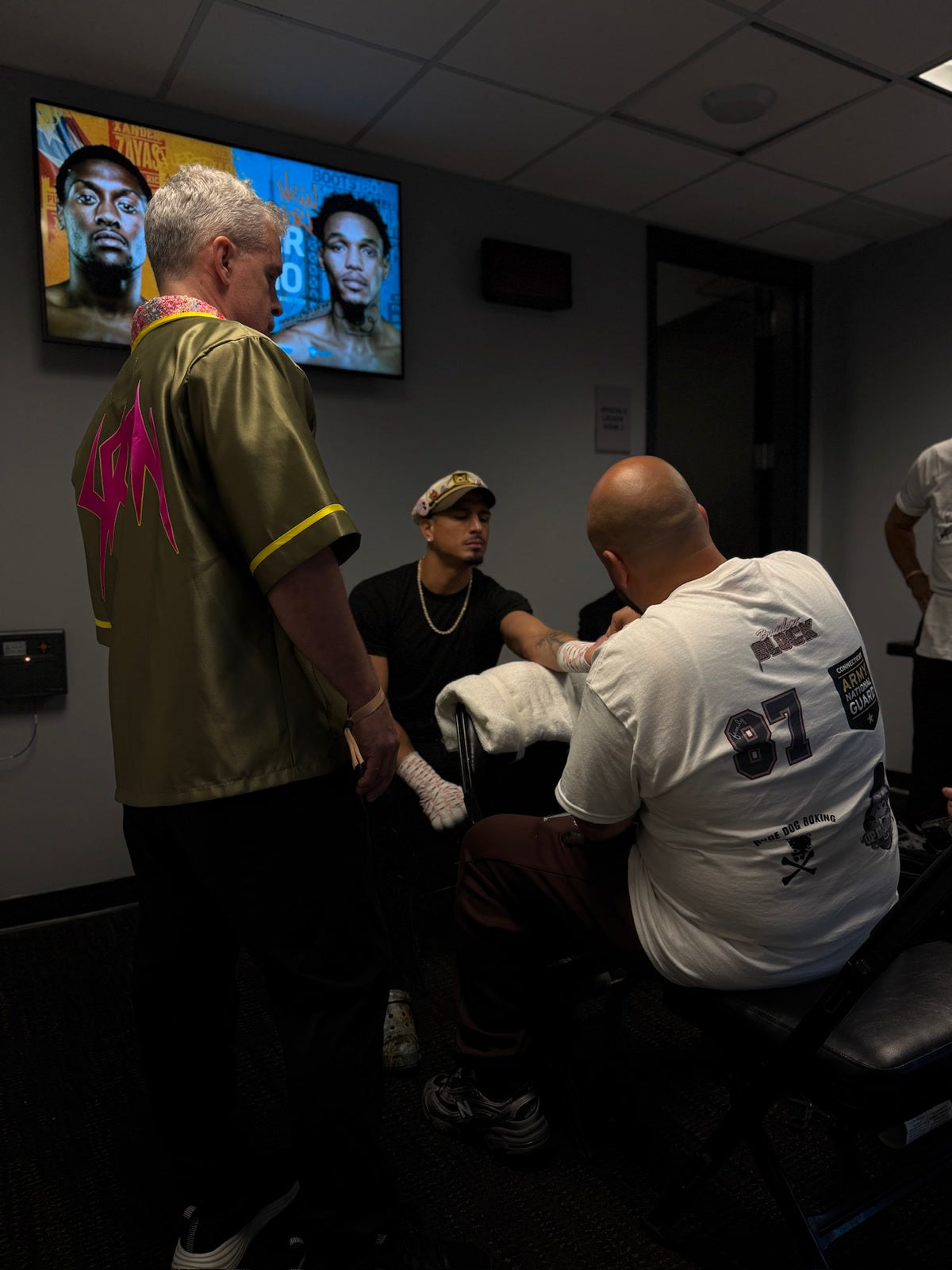 Richard Rivera's hands being wrapped backstage at Barclays Center by his cornerman in a BOXELITE 87 Connecticut Army National Guard shirt with Lou DiBella looking on