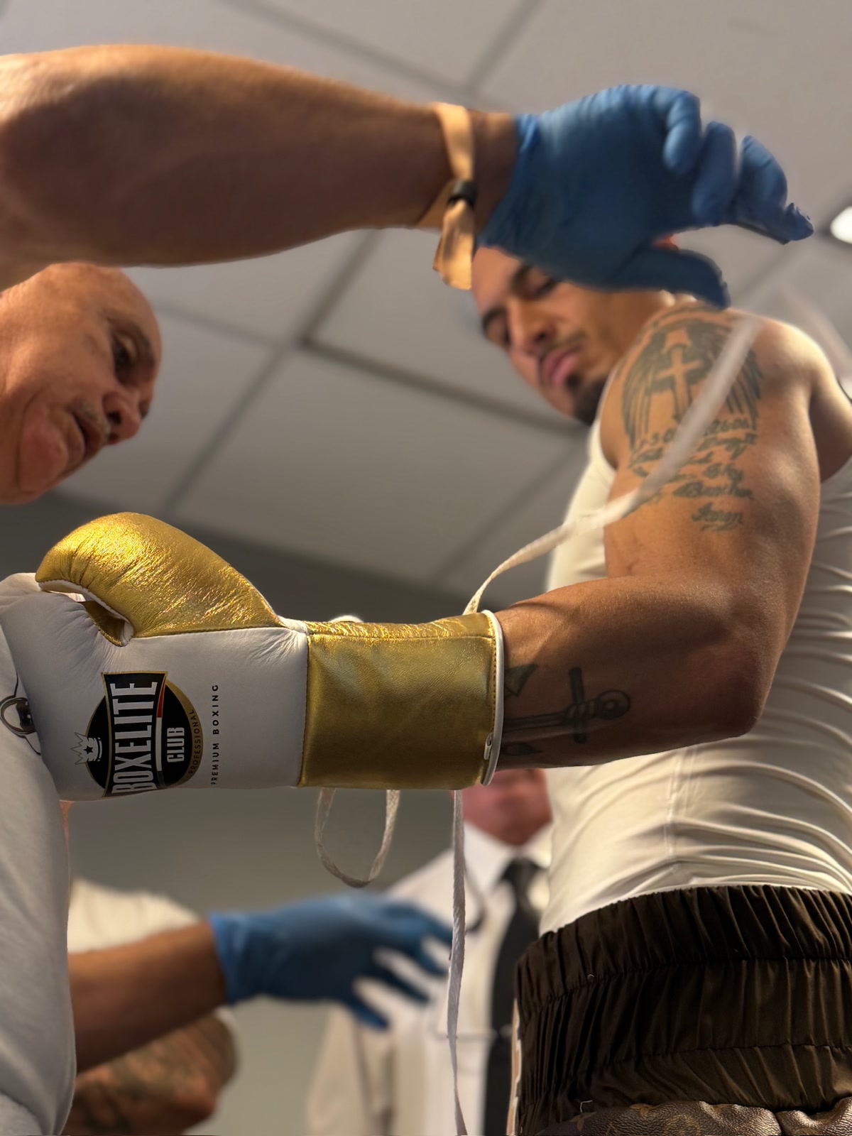 Close-up of the BOXELITE Club Professional Premium Boxing 10oz glove in white and gold being laced up on Richard Rivera before the Whittaker fight